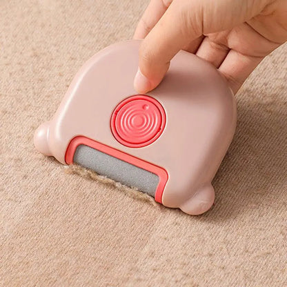 Hand pressing the pink mini pet hair remover brush onto a beige carpet.