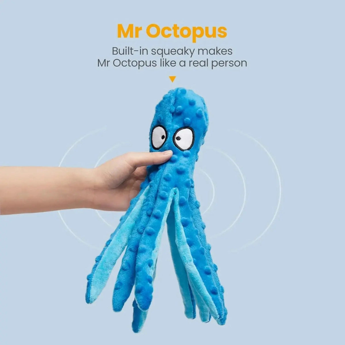 Hand pressing the head of the blue octopus dog toy to work the built-in squeaker.