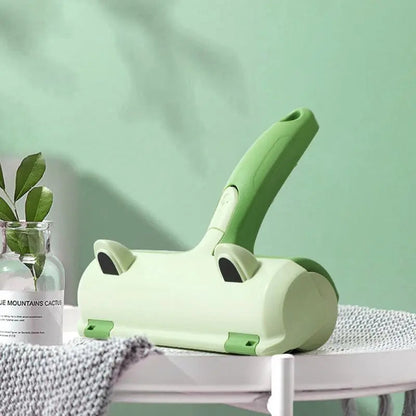 Green reusable pet hair remover brush on a side table beside a gray knit blanket.