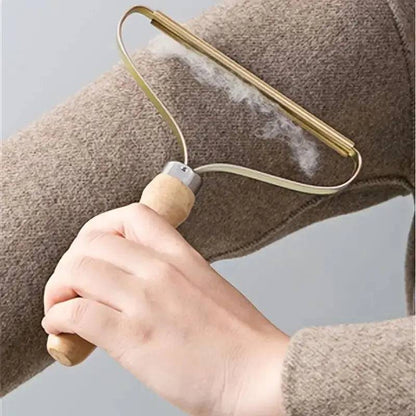 Fabric shaver lifting a line of fluff from the sleeve of a beige knit sweater.