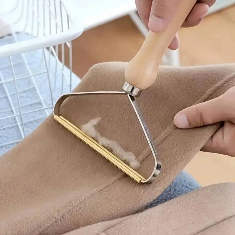 Fabric shaver clearing pills and fluff from a camel wool blanket held taut by hand.