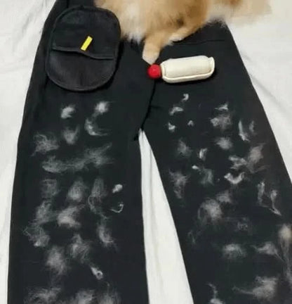 Cat hair covering a pair of black trousers beside the Noblias pet hair remover glove.