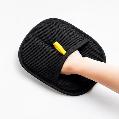 Hand wearing the black electrostatic pet hair remover glove with a yellow pull tab on a white background.
