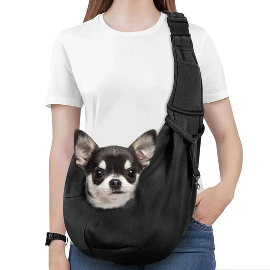 Woman wearing the black pet sling carrier across her body with a chihuahua's head resting out of the opening