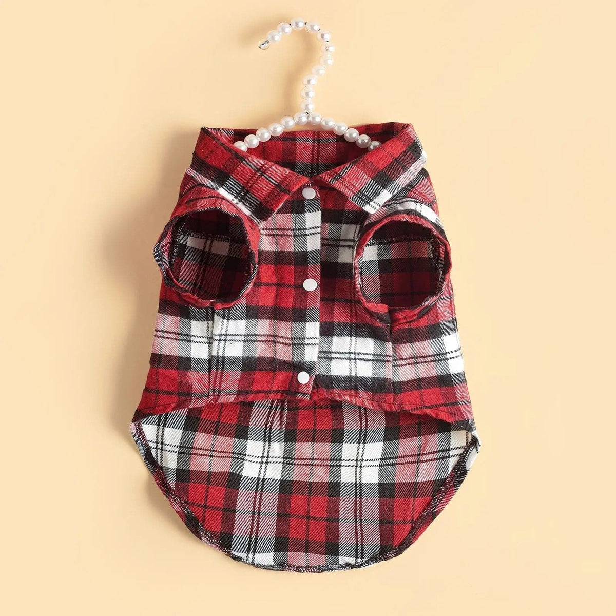 Red plaid flannel dog shirt on a hanger showing the button front, collar and curved hem.