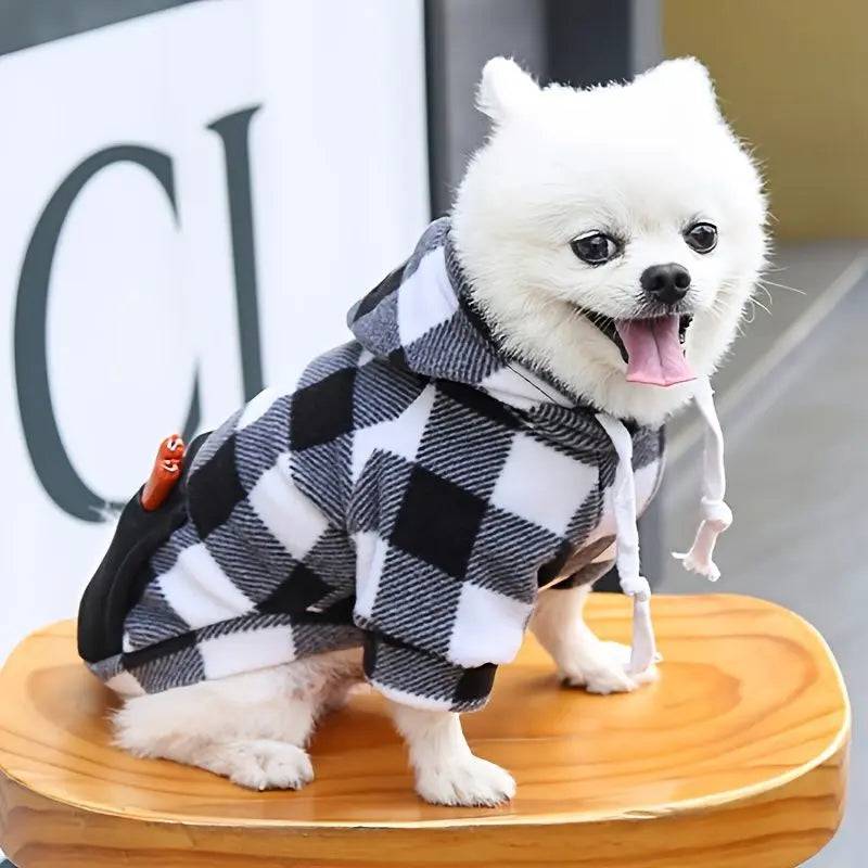 Side view of a white Pomeranian in the black and white plaid fleece dog hoodie with the hood and drawstring.