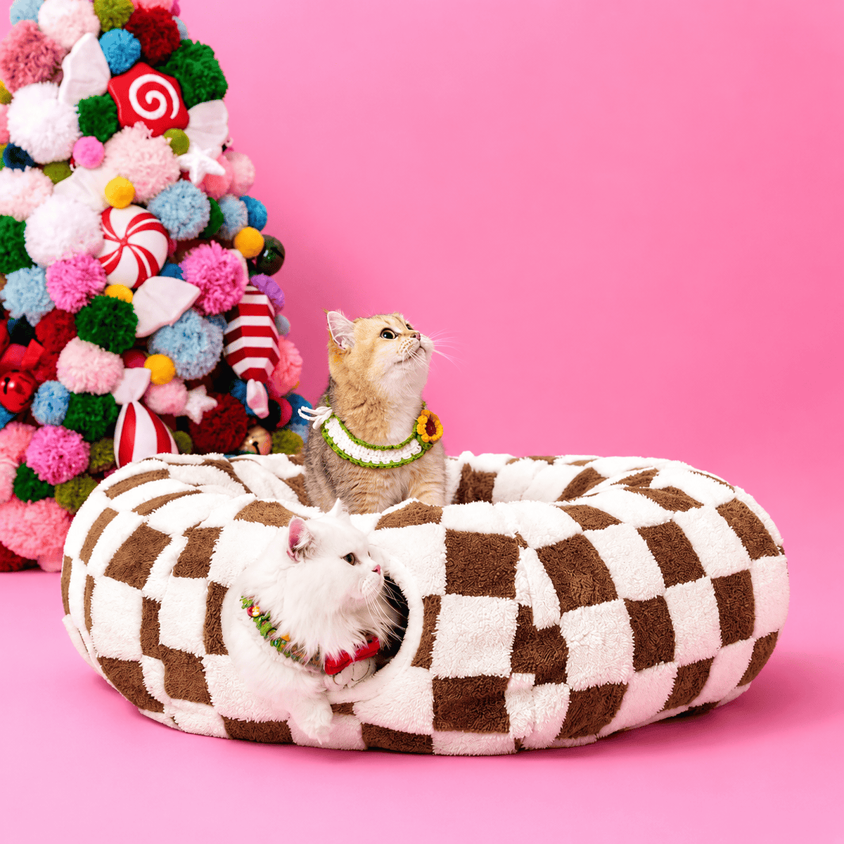 Coffee brown checkerboard plush cat tunnel bed with a white cat looking out of the tunnel opening