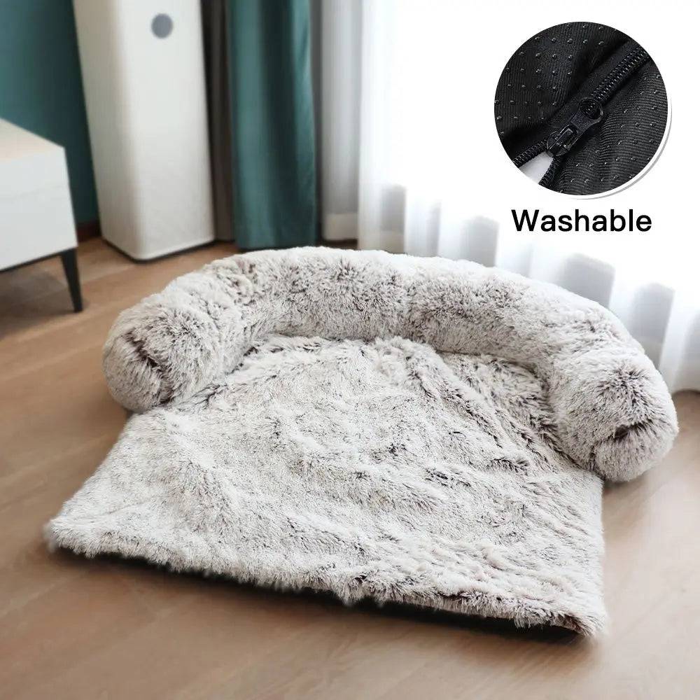 Light coffee ombre plush dog couch bed with its U-shaped bolster and washable zip cover, on a wood floor.