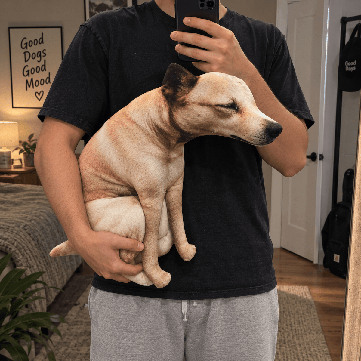Man holding the large funny pooping dog plush toy in one arm for a mirror photo.