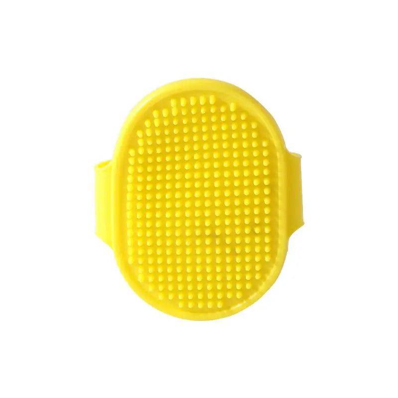 Yellow oval rubber pet bath brush with its molded hand strap, shown face on against a white background.