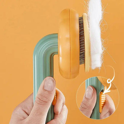 Self cleaning cat slicker brush with the pins retracted and a sheet of white fur lifting off, with the side release lever shown.
