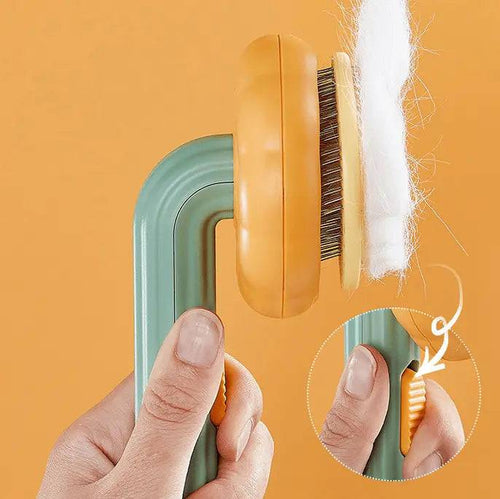 Self cleaning cat slicker brush with the pins retracted and a sheet of white fur lifting off, with the side release lever shown.