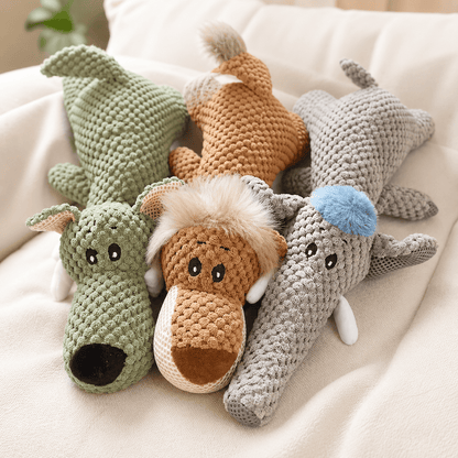 Green wolf, orange lion and gray elephant squeaky plush animal dog toys lying together on a sofa.