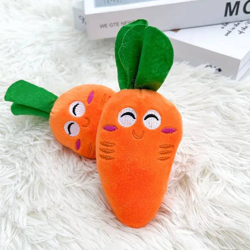 Two orange plush carrot squeaky dog toys with embroidered eyes and green fabric leaves.