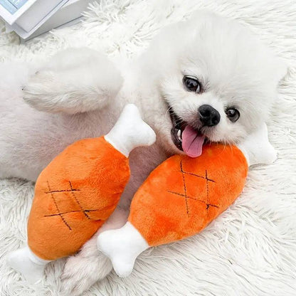 White Pomeranian lying on a rug with two plush chicken leg squeaky toys.