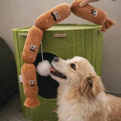 Corgi sniffing the four link sausage dog toy draped over a green pet house.