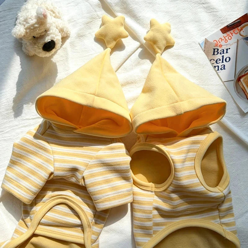 Close-up of two striped dog pajamas with yellow lined hoods and star toppers.