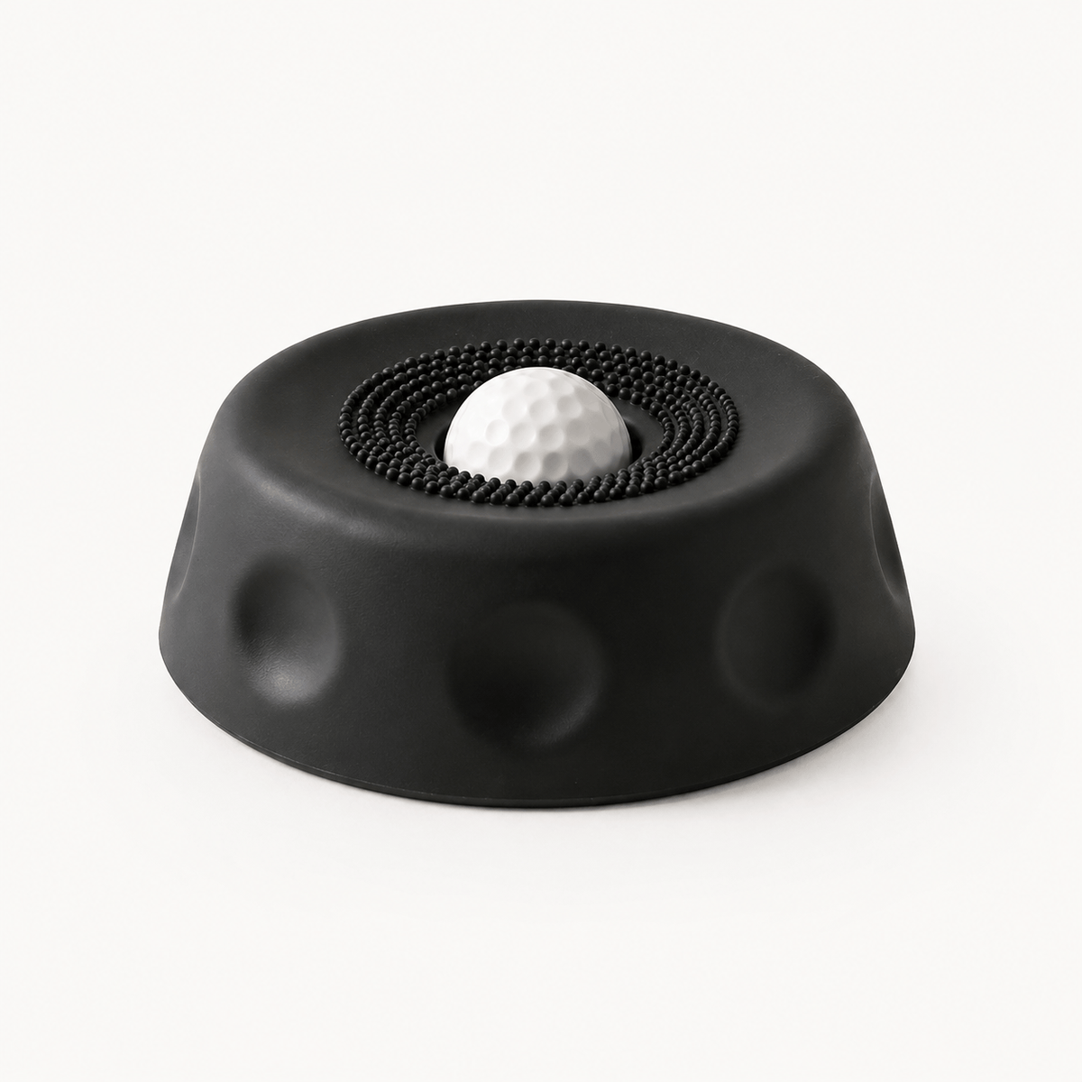 Black suction dog lick bowl with a white rolling ball on a cream background.