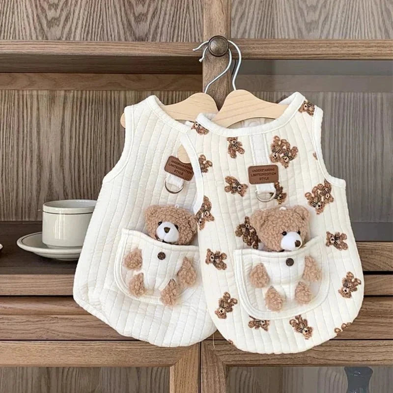 Bear print and solid white dog harness vests hanging on a hanger