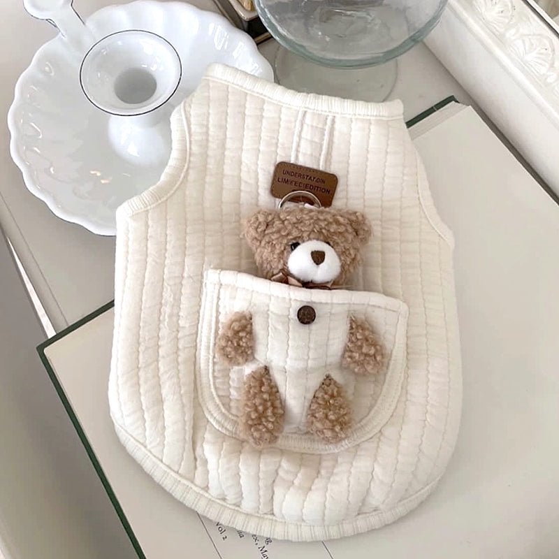 Solid white quilted dog harness vest with a plush teddy bear in the pocket