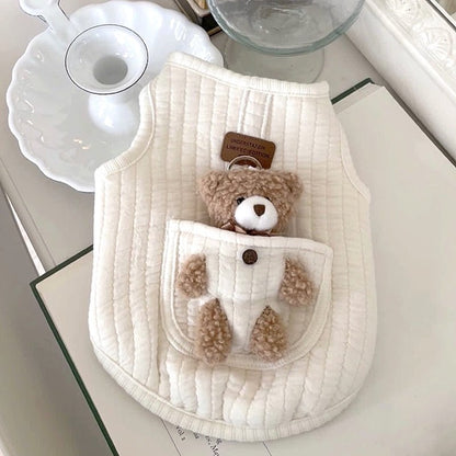 Solid white quilted dog harness vest with a plush teddy bear in the pocket