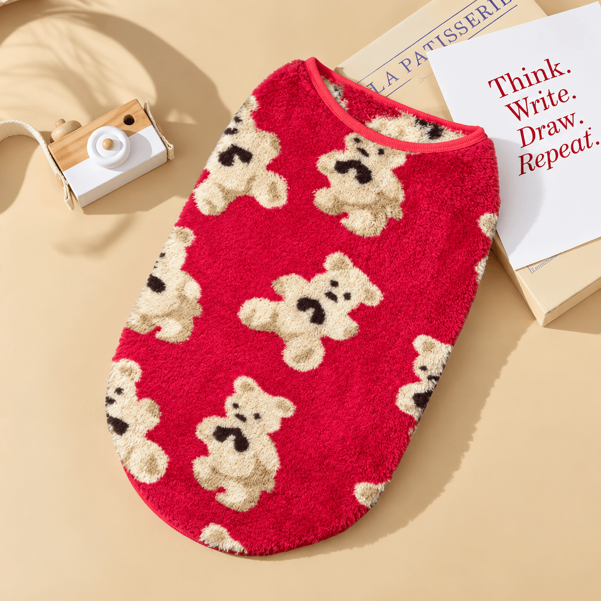 Red teddy bear fleece dog vest with cream bears laid flat.