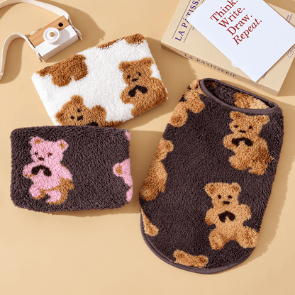 Flat lay of three teddy bear fleece dog vests in white, brown with pink bears and brown with tan bears.