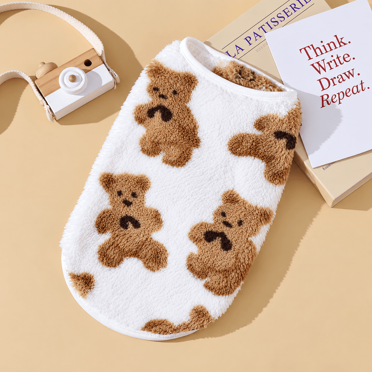 White teddy bear fleece dog vest with brown bears laid flat.