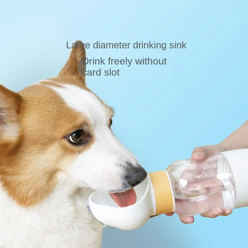 Corgi drinking from the white cloud-shaped cup of the travel dog water bottle held in a hand.