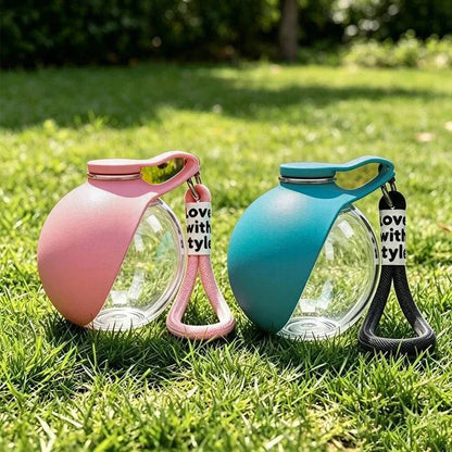 Pink and blue travel dog water bottles with silicone sleeves and Love with Style lanyards standing on grass.